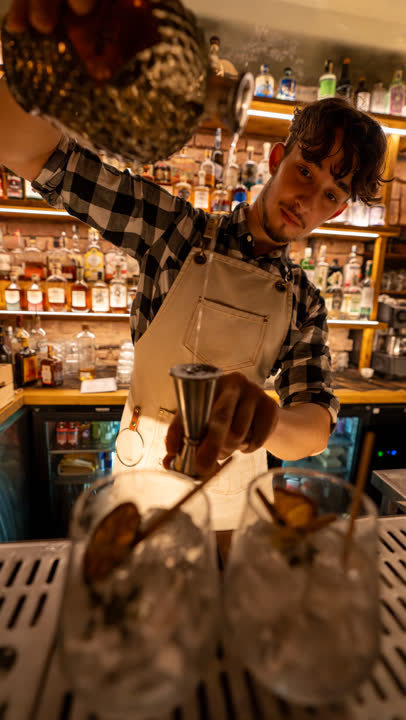 Bartender při nalévání drinku v portrétním formátu.