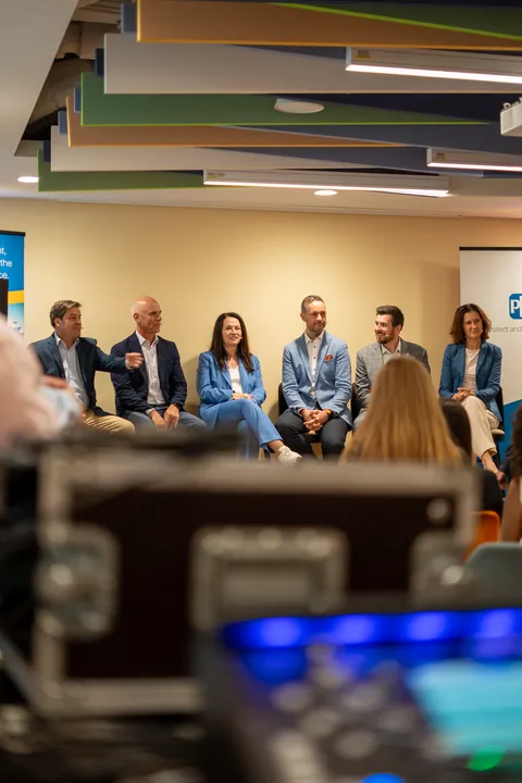 People in a conference room with recording equipment in the foreground.