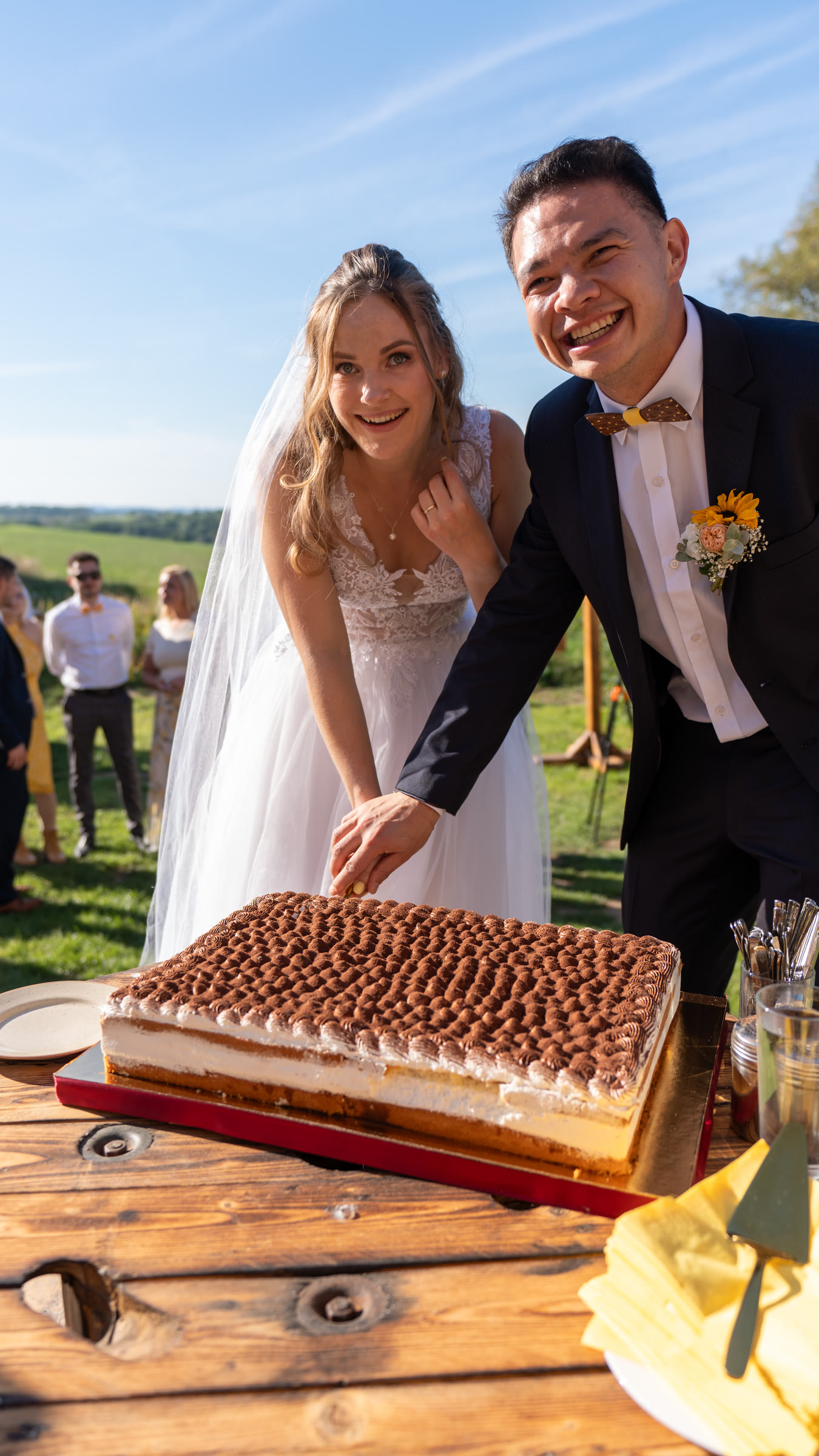 Lukáš and Míša cutting their wedding cake outdoors.